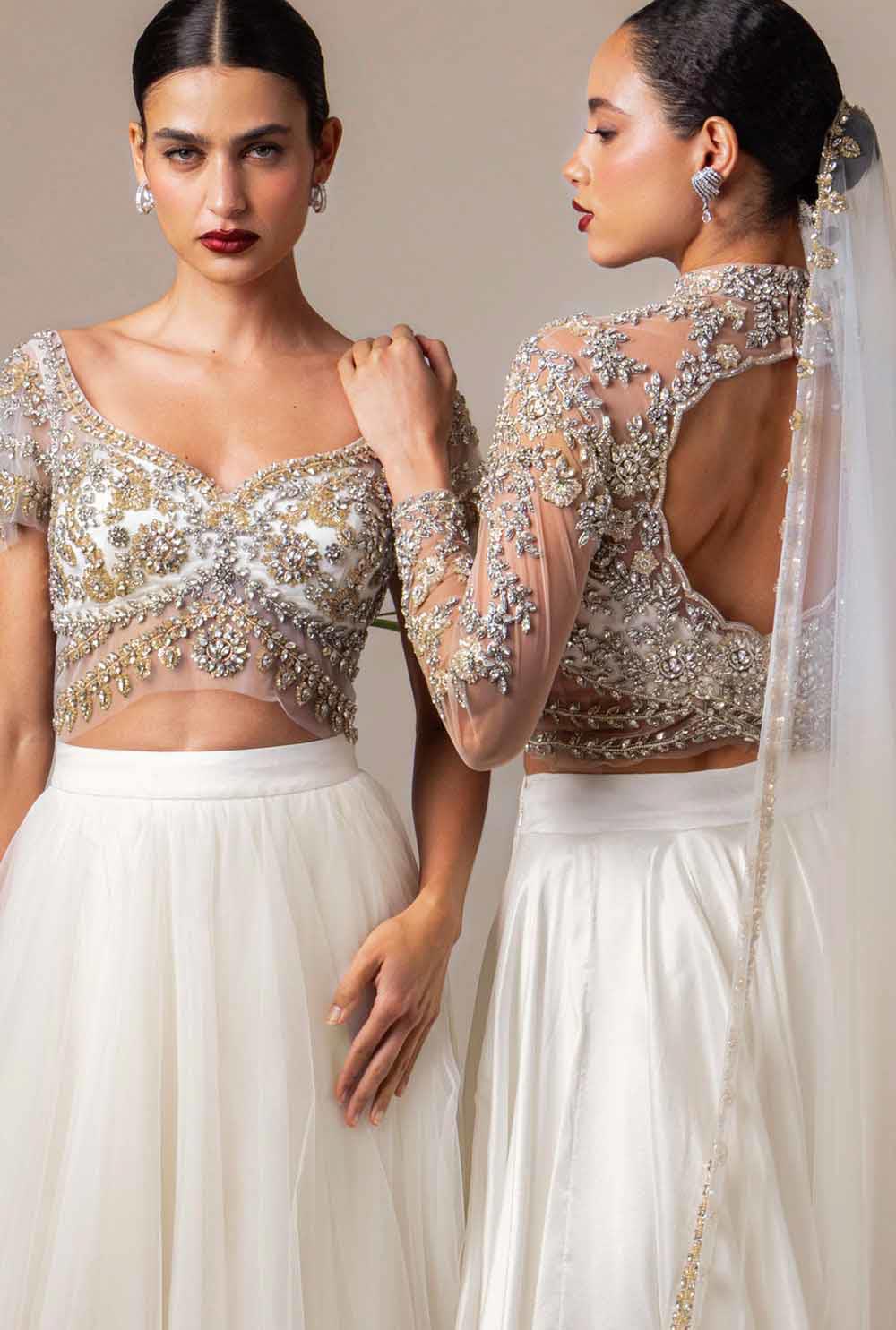 Two brides wearing white skirts with intricately hand embroidered bridal blouses and delicate dupattas.